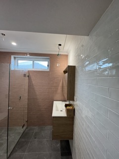 Overhead wet zone illumination highlighting precise tile mitring and joint alignment.