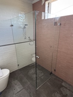 Curbless, hobless walk-in shower with minimalist linear drain and refined tapware.