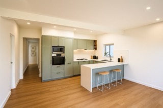 The new open-plan living, dining, and kitchen layout beneath the engineered LVL beam.