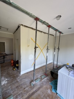 Engineered temporary structural propping carrying roof load prior to wall removal.