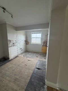 Stripped kitchen cavity revealing uneven substrate and masonry.